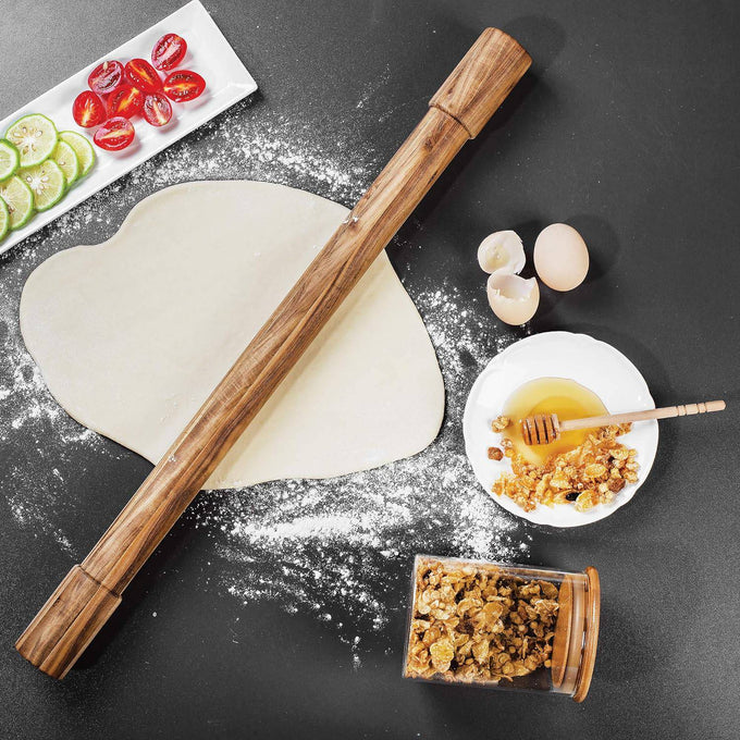 Handcrafted acacia wood rolling pin with fixed handles resting on rolled dough sprinkled with flour, surrounded by eggs, honey with nuts, granola, and sliced fruit, ideal for Kitchen & Food, Cookware, Baking Supplies, Best Sellers, and Promo Eligible collections.